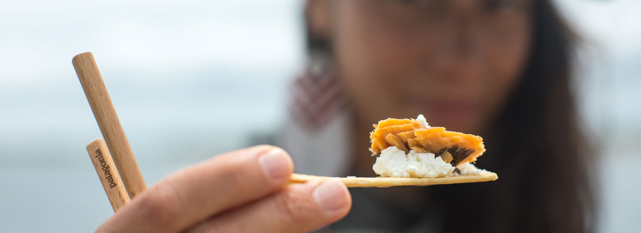 Juanita Ah Quin holds out a cracker topped with goat cheese and pink salmon